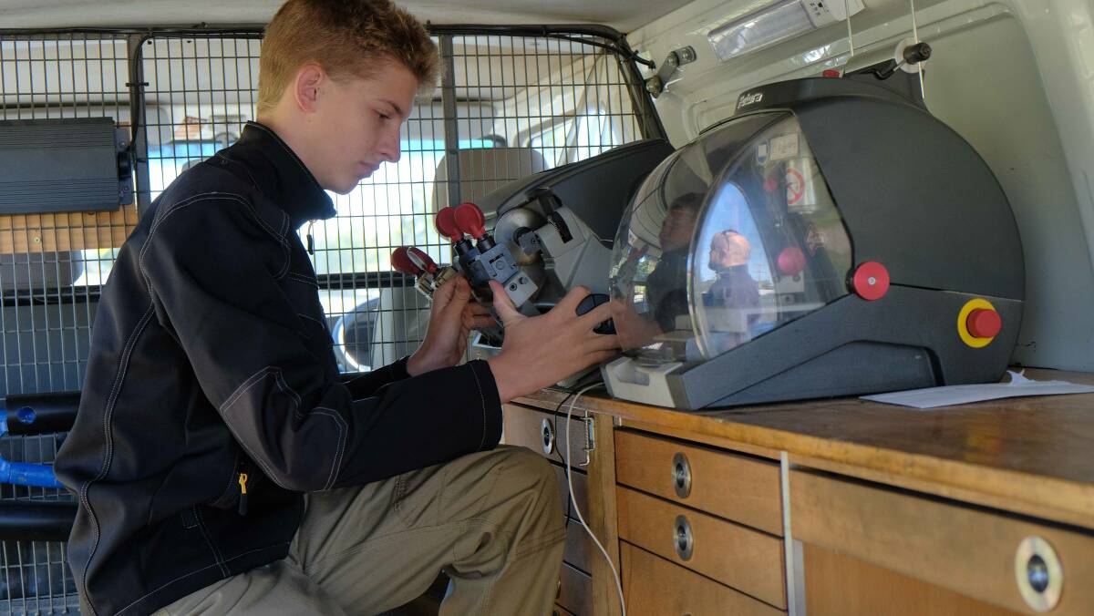 LINK PROGRAM: Conor England cutting a key in the back of the locksmith van. Photo: supplied.