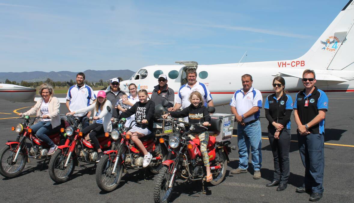 FIRST FLIGHT: Sarah Patterson (on postie bike on right) and her family were the first passengers to fly out of Mudgee with Wings 4 Kidz, pictured with pilots and Late Mail riders.