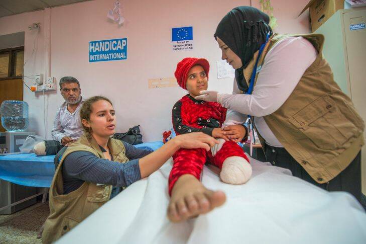 Nada undergoes physiotherapy at the EU-funded Muharabeen primary healthcare centre in East Mosul, while her father has his dressing changed. Credit Peter Biro/ECHO/EU