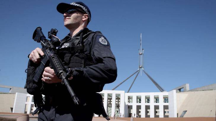 An AFP officer armed with a machine gun patrols outside the front of Parliament House. Photo: Andrew Meares