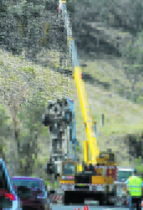 A crane raises the damaged vehicle following a crash on the Castlereagh Highway south of Mudgee on Saturday.