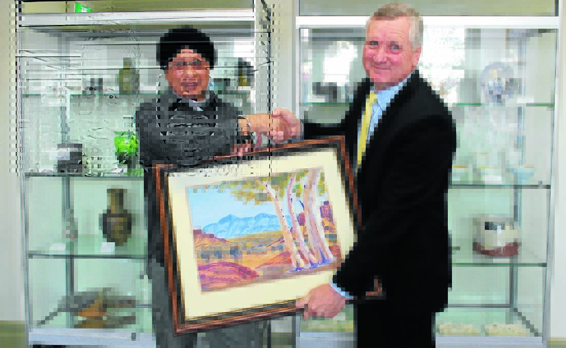 Gora Singh Mann and Mid-Western regional Council general manager Brad Cam will the Noel Raggett painting Mr Mann has donated to council’s art collection.