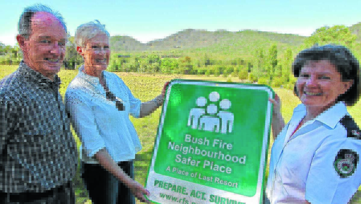 ONE OF TEN: Inspector Jayne Leary (right) shows Trevor and Jayne Ivers the type of sign that will shortly be installed at the gate of their property on Riverlea Road to identify their open paddocks, seen in the background, as a Neighbourhood Safer Place where people can seek shelter as a last resort in the event of a bush fire. 