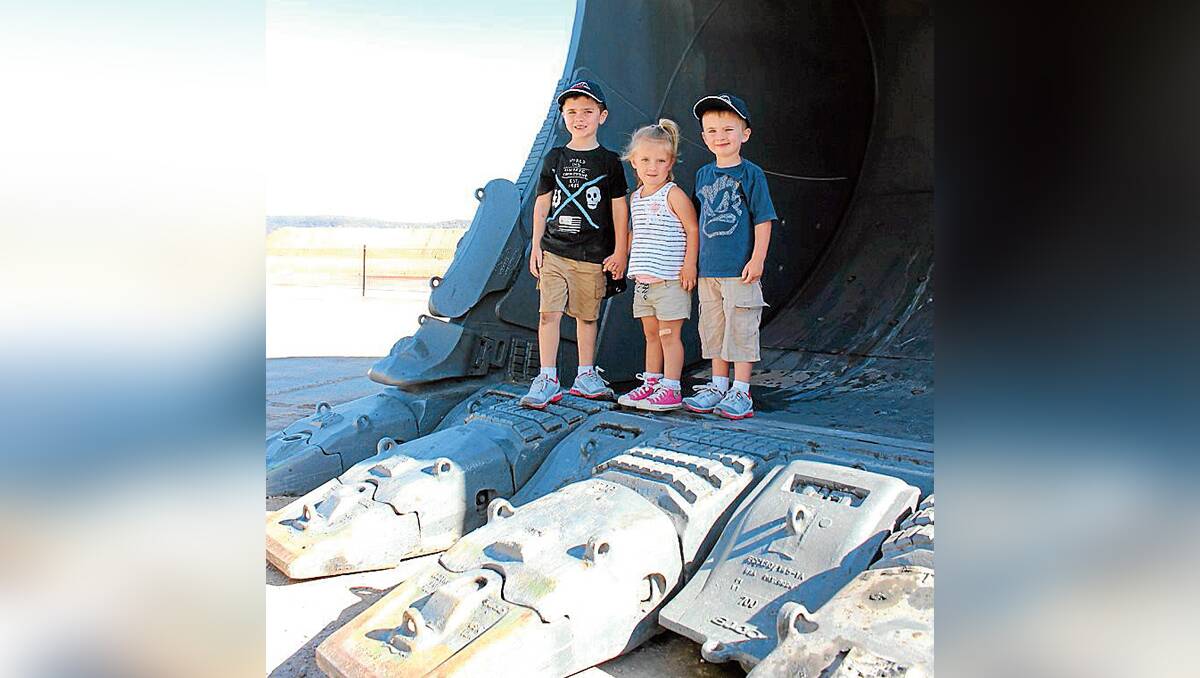 Luke, William and Emily Reiss stand in the bucket on the new excavator at Moolarben.