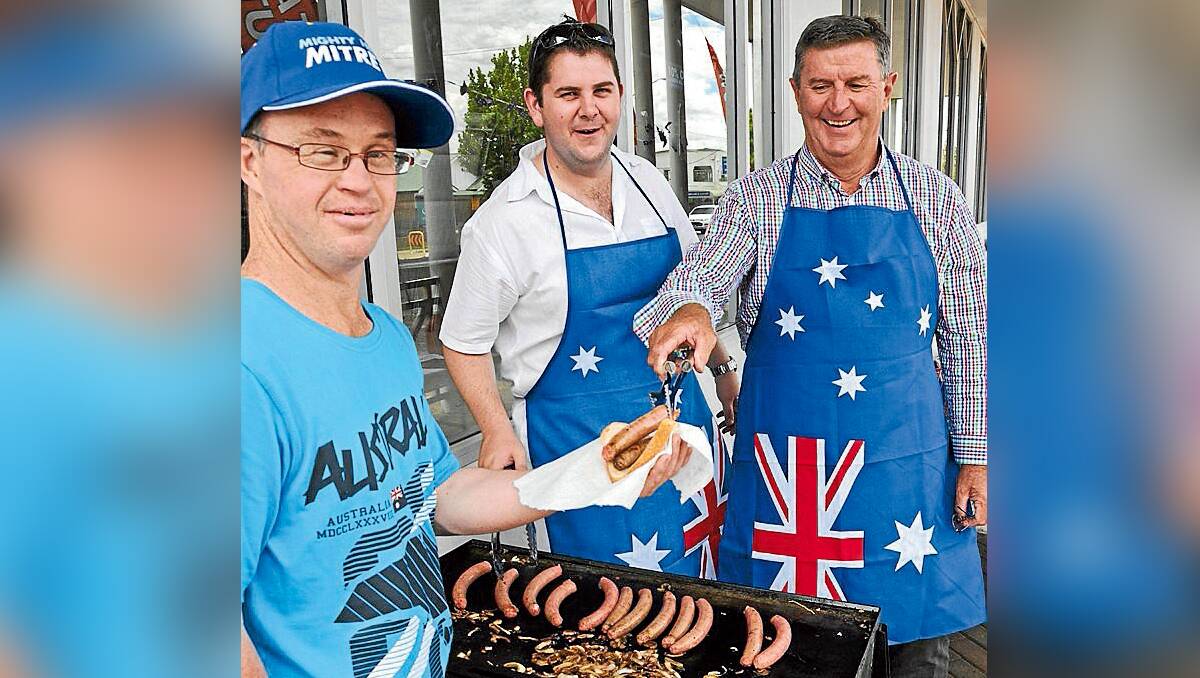 Councillor Paul Cavalier and Mayor Des Kennedy serve local John Malone at the Petrie’s Mitre 10 Coonabarabran bushfire appeal barbecue on Saturday.	270113/SSPetrie’sBBQ