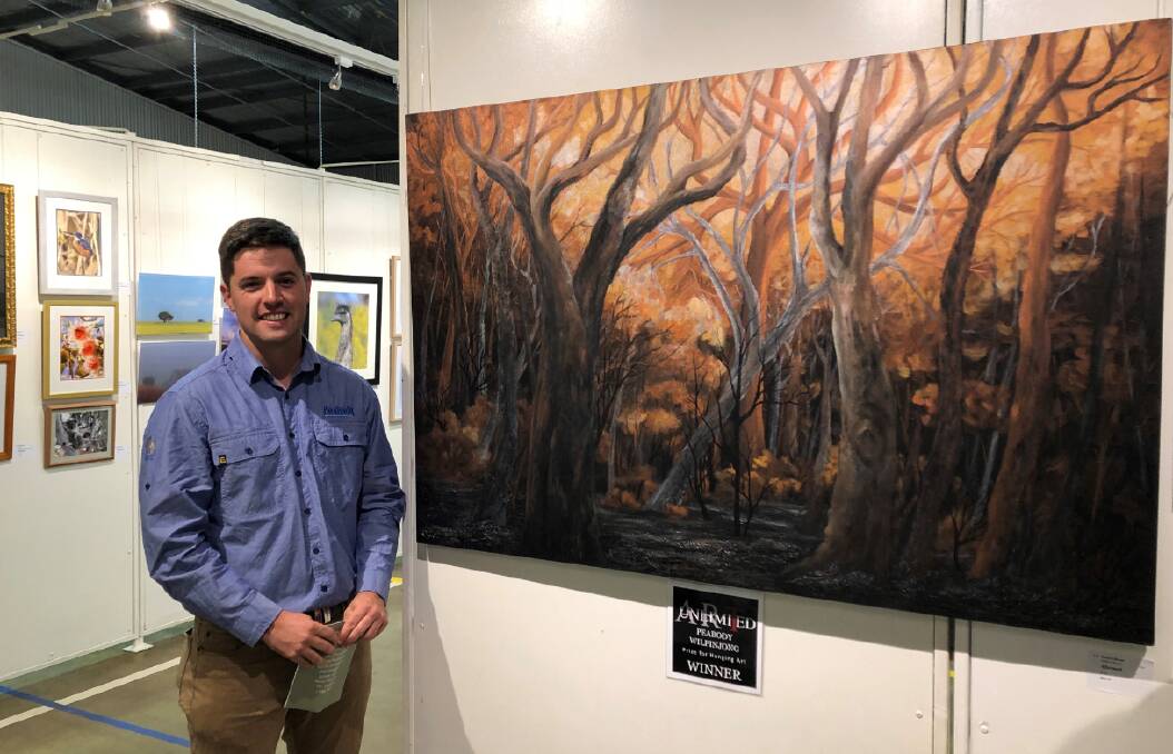 Wilpinjong Mine environmental advisor Josh Frappell stands next to "Aftermath", by Eleanor Anson, which won the Peabody Wilpinjong Prize for Hanging Art. Photo: Supplied.