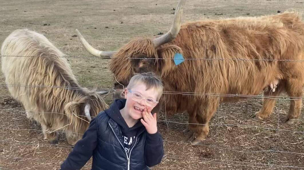 Charlie Swords having fun with some cows. Picture supplied by Down Syndrome NSW