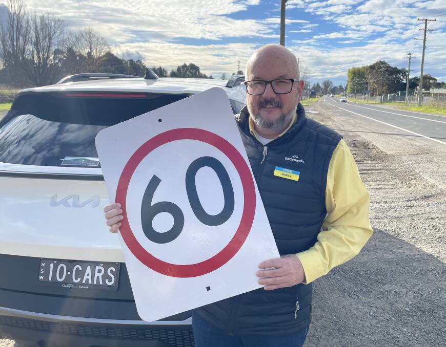 Road safety expert Matthew Irvine holding a 60 kilometre sign on the side of the road. Picture: Bradley Jurd
