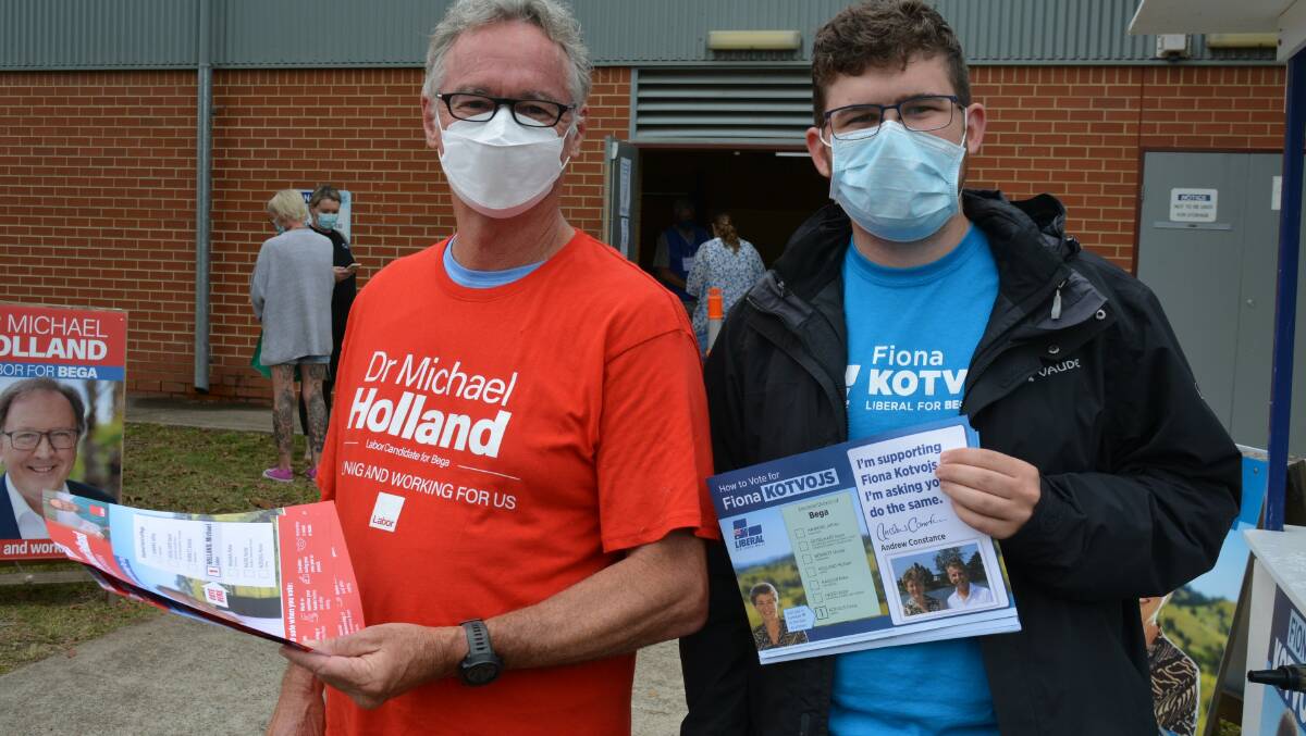 Bruce Hartican and Samuel More offer how-to-vote cards for candidates Michael Holland (Labor) and Fiona Kotvojs (Liberal) at Bega High School on February 12. Photo: Ben Smyth