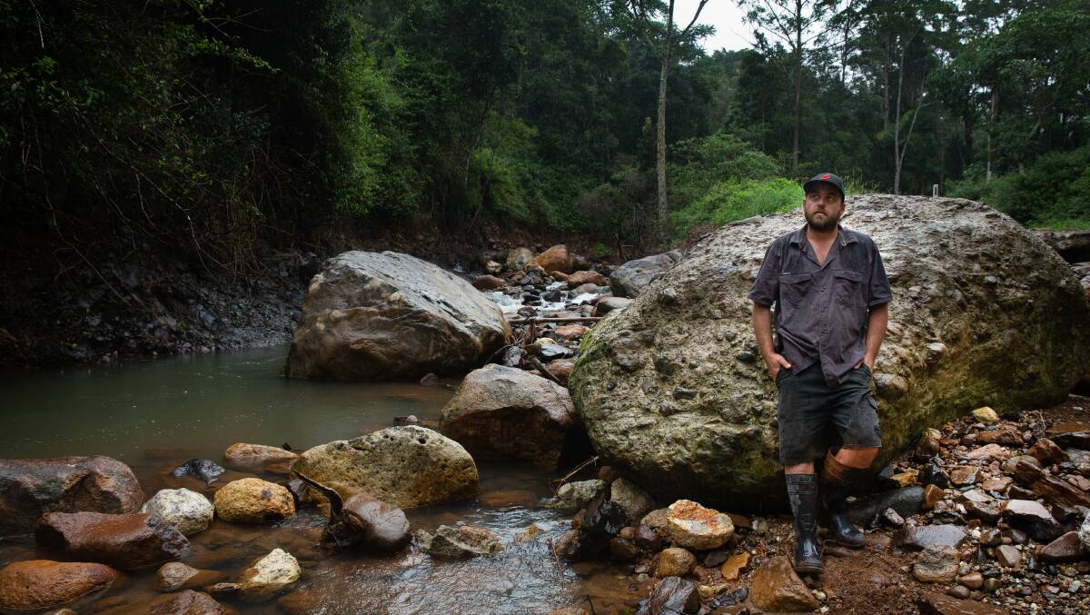 Jaye Dunlop in front of one of the massive boulders which was washed down the creek during the February 28 deluge. 