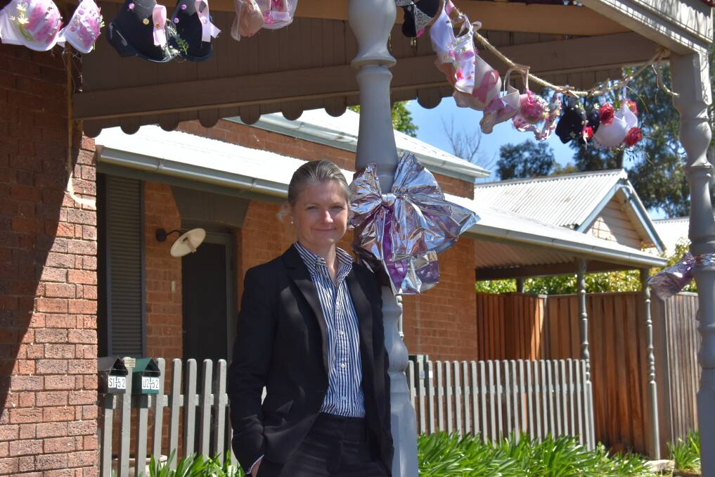 BRAS: Edwina Smith in front of a row of hanging bras at the Signature Properties Mudgee office. Picture: JAY-ANNA MOBBS