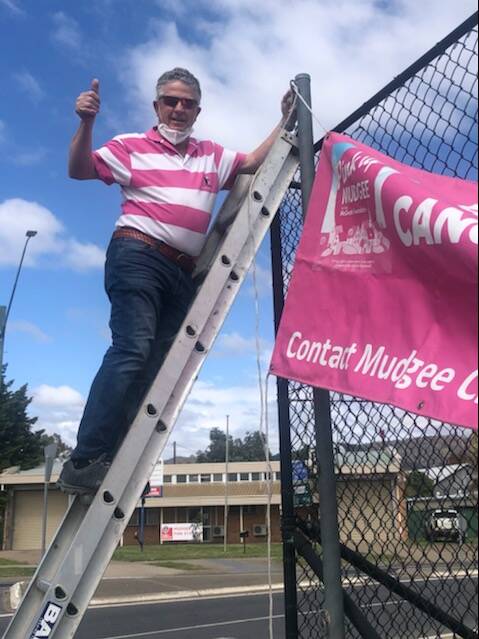 Hugh Bateman putting up the Pink Up sign at the Mudgee tennis courts.