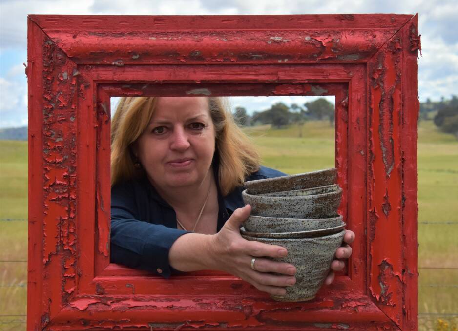 IN FRAME: Catherine Sykes with some of her wheel thrown bowls peering through red a picture frame. Picture: JAY-ANNA MOBBS
