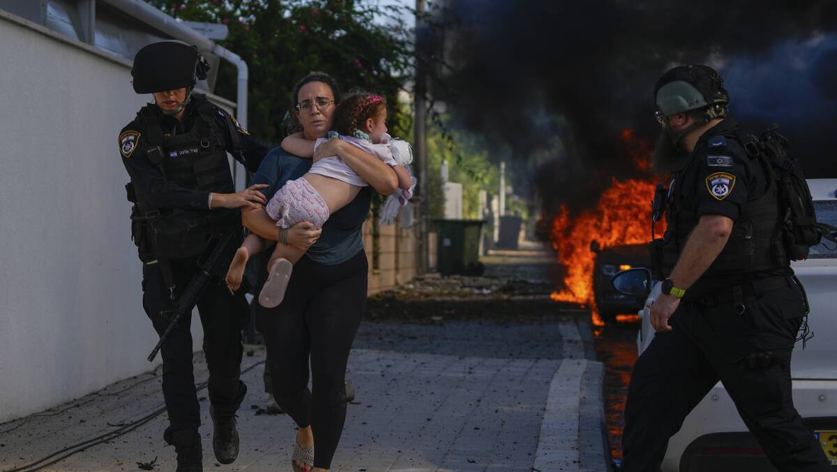 Police officers evacuate a woman and a child from a site hit by a rocket fired from the Gaza Strip over the weekend. Picture AAP