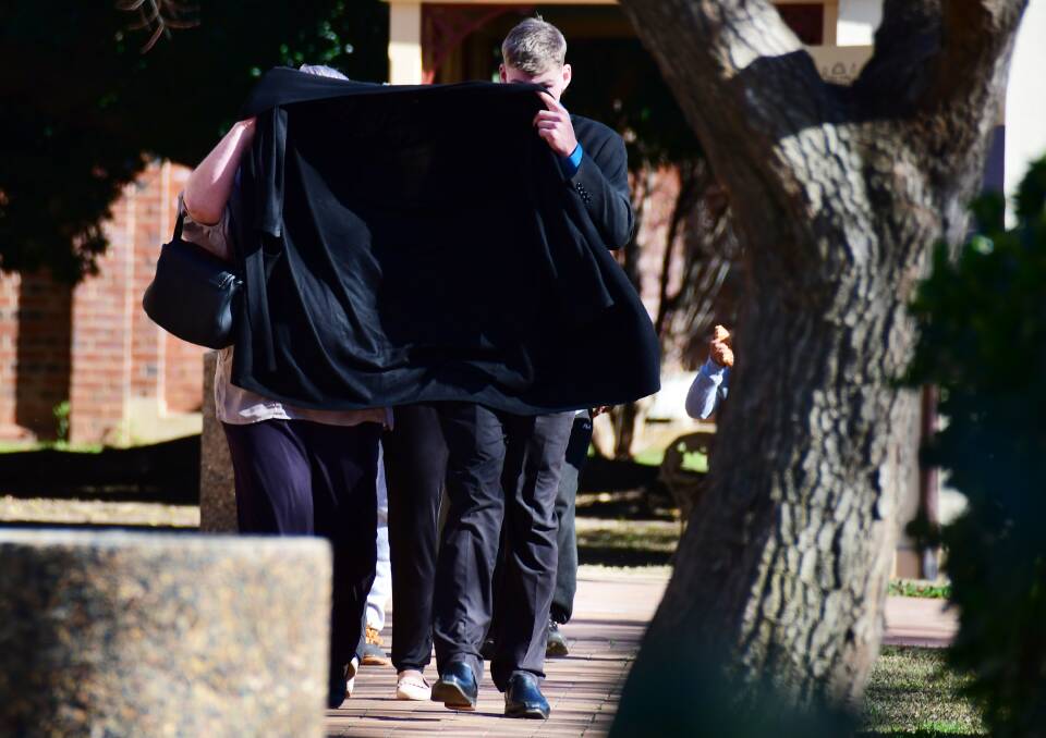 DUCKING FOR COVER: Alleged emu plucker Jye Leslie Schultz tries to cover his face up as he leaves Dubbo court. 