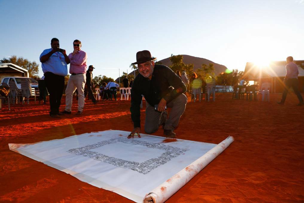 FROM THE HEART: Noel Pearson signs the canvas last week on which the Uluru statement will be painted. Photo: Alex Ellinghausen