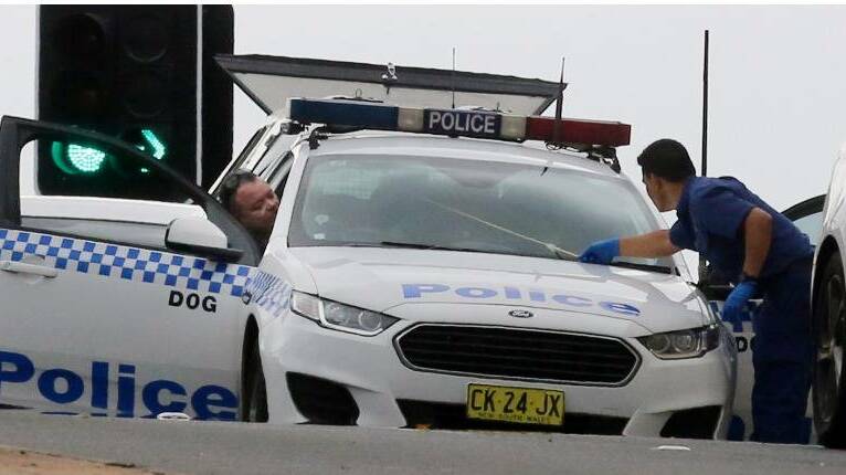 Police examine a bullet hole made in the windscreen of a passing police car. 