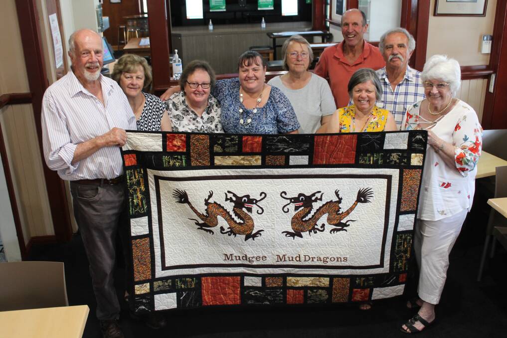 MudDragons members Chris and Pam Bellhouse (left and right) present the club with the quilted banner they made, which will be used when they set up a site at events.