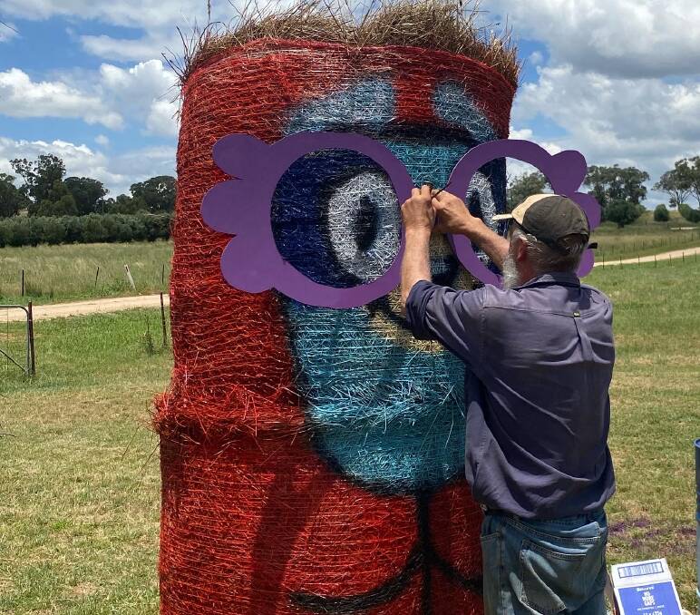 Terry Rheinberger placing the hand-made glasses on the painted hay bale. Photo: Submitted / Keira Underwood