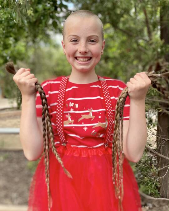 A post head shave Piper holding her plaits. Photo: Supplied