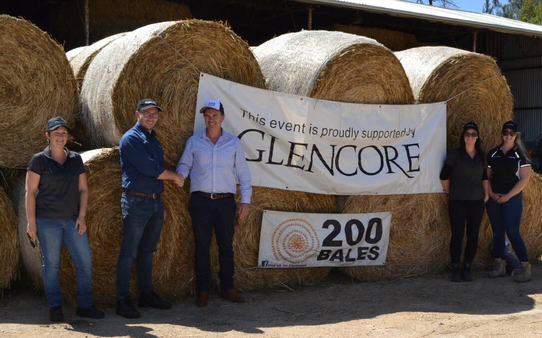 Glenn Box with representatives from Glencore standing in front of a whole stack of hay destined for farmers. Photo: Supplied