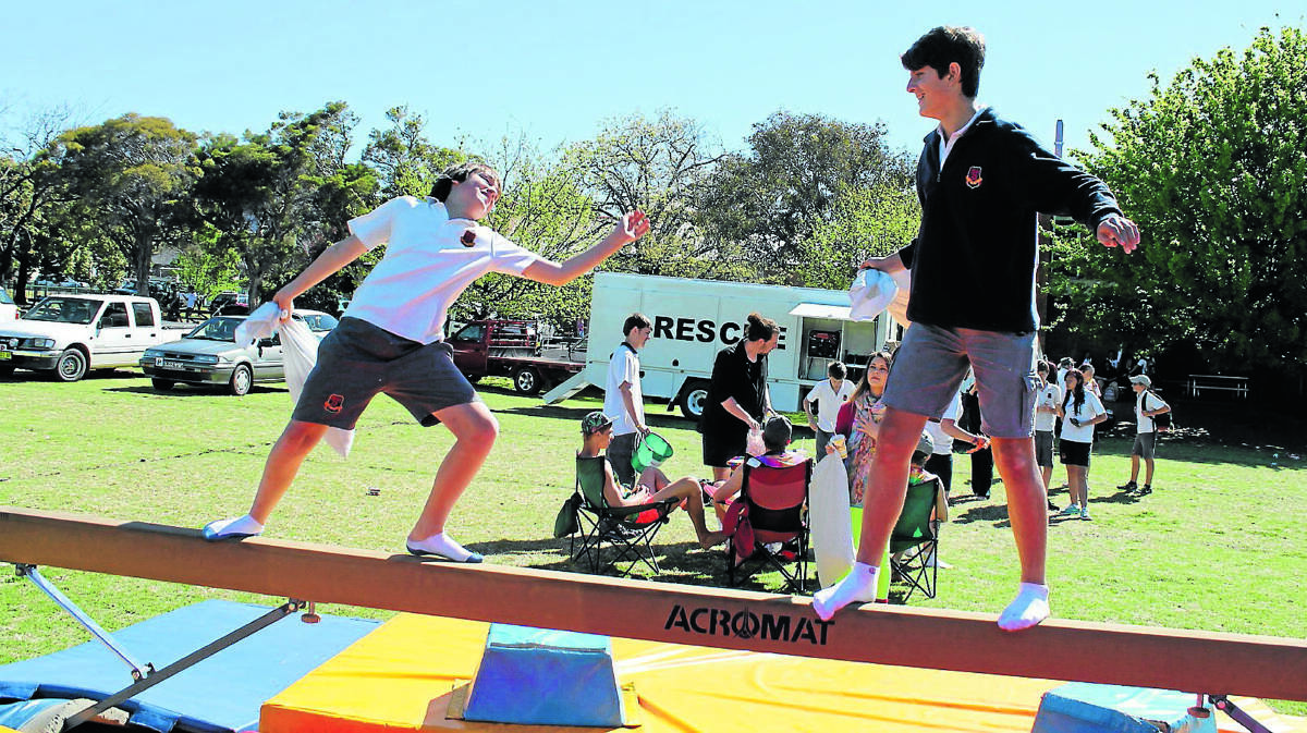 BIG SWING: Daniel Walters lines up Josh Sandry in the balance beam pillow fight game at the Rainbow Day Fete.