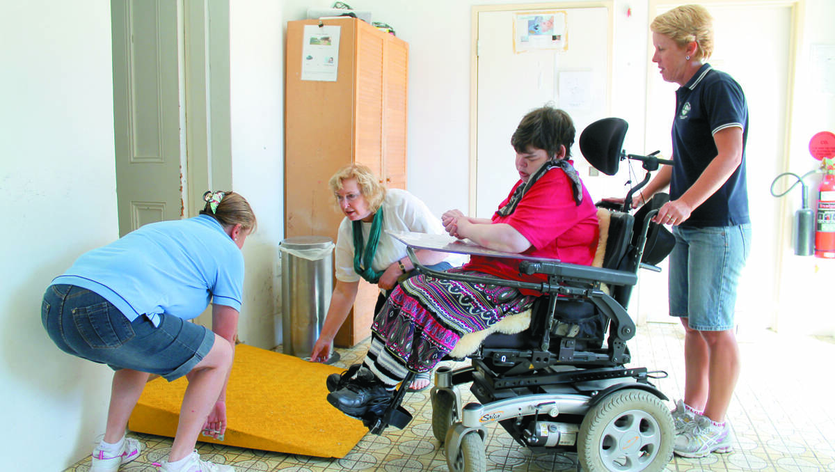 Janet Stait and Carolyn Peek lay down a ramp for Tracy Solway and Vickie George in the current Lifeskills facility, which was not built for people with disabilities. 	110213/lifeskills/1