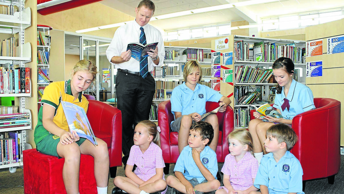 ALREADY READING: St Matthew’s junior captain Georgie Haigh reads to young students (from left) Ruby Maguire, Hugh Portelli, Mia Halpin, and Oliver Turner, while principal Jason Hanrahan and senior captains Jesse Woods-Smith and Grace McLean brush up on some reading. Next week the school will be celebrating Catholic Schools Week and one of the activities will be World Read Aloud Day on Wednesday.	050313/spStMattsCSW/007